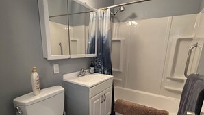 Baño con inodoro, lavamanos, espejo y ducha.