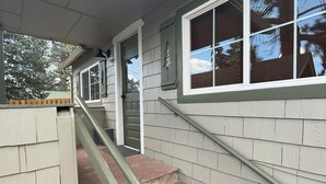 Un escalier avec une rampe menant à une porte, le tout entouré de murs recouverts de bardage.