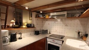 Eine Küche mit Mikrowelle, Toaster, Kaffeemaschine und Backofen. Holzschränke und eine Arbeitsplatte sind vorhanden.