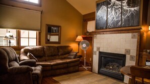 Una sala de estar acogedora con un sofá de cuero, una chimenea y un cuadro abstracto grande en la pared.