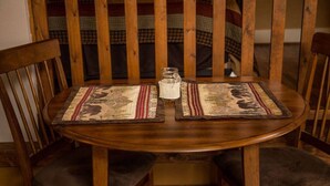 Una mesa de madera con dos individuales, un tarro de cristal y una manta escocesa al fondo.