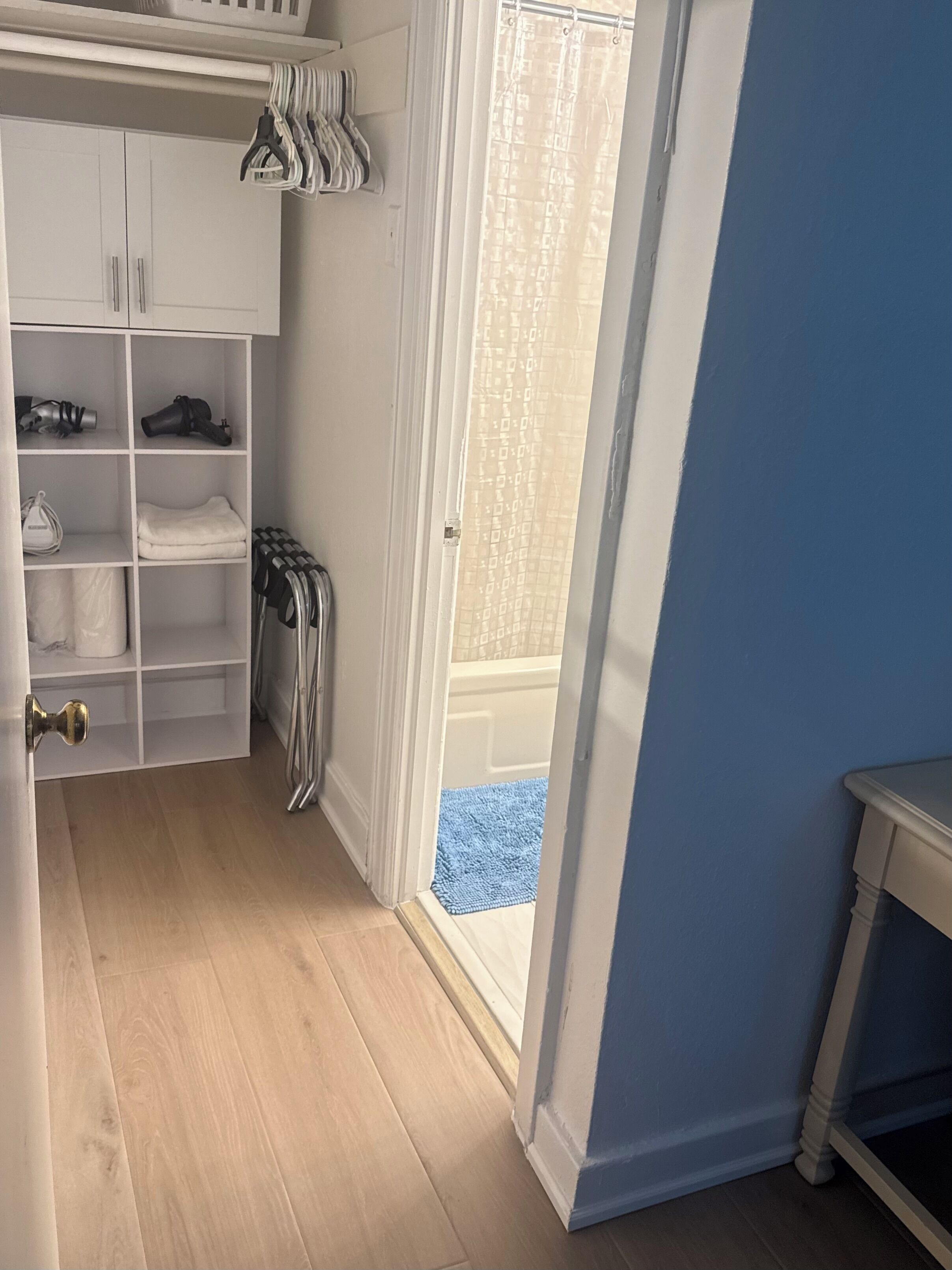 A room with a white wardrobe, a blue wall, and a wooden floor.