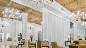 A spacious lobby with high ceilings, chandeliers, and a mix of seating arrangements including sofas and armchairs.