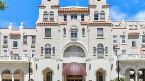 A large, white building with a symmetrical facade, multiple windows, and a central entrance with a red awning. - TROPICAL PALM BEACH SUITE- 3 BEDS 2BEDROOMS 2BATHS POOL,BEACH,FRONT DESK 24/7 (PALM BEACH)
