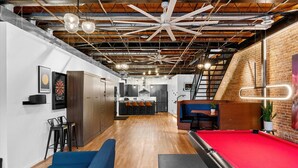 A modern indoor space with a pool table, seating area, and a kitchen in the background.