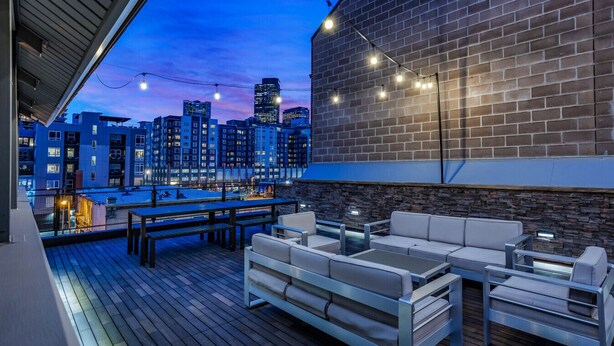 An outdoor deck with a city skyline view, a brick wall, and outdoor seating.