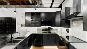 A modern kitchen with black cabinets, a stainless steel sink, and a built-in oven.
