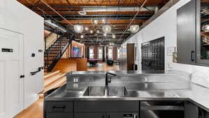 A modern kitchen with stainless steel appliances, a double sink, and a wooden ceiling.