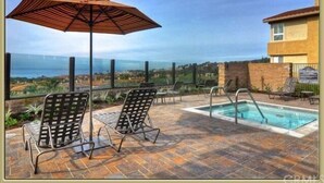 Eine Dachterrasse mit Pool, Liegestühlen und Sonnenschirm.