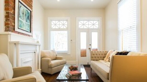 A living room with a fireplace, two sofas, a coffee table, and a door with decorative glass panels.