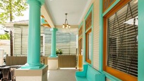 A covered outdoor area with teal-colored columns and wooden window frames.