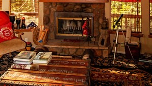 A cozy living room with a stone fireplace, books, and a telescope. - Indian Heaven Treehouse-Nightly Shooting Stars, Miles of Balconies & Rock Views  (Idyllwild)