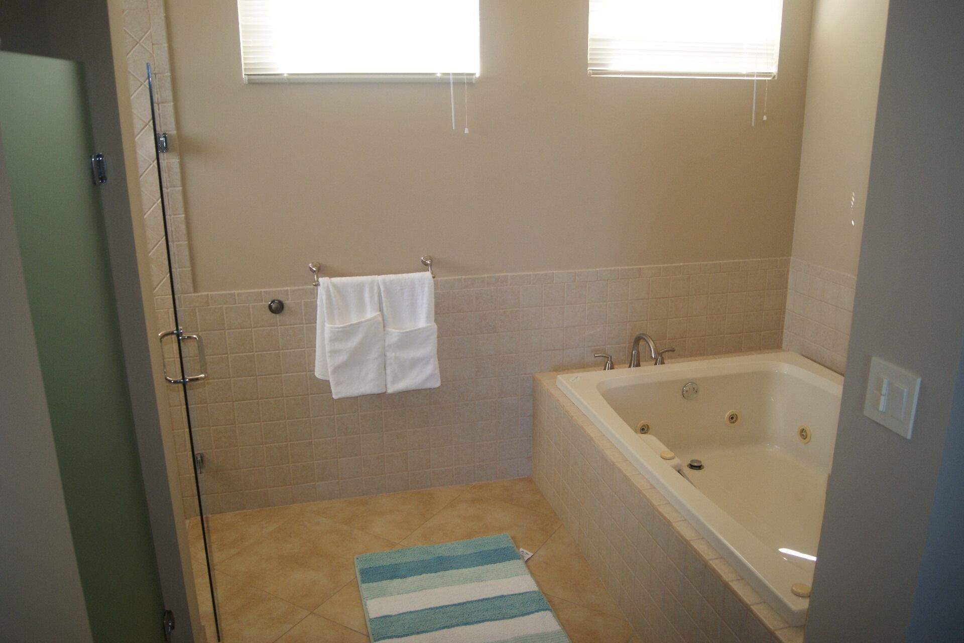 Een badkamer met een badkuip, een douche en een handdoekrek met twee handdoeken.