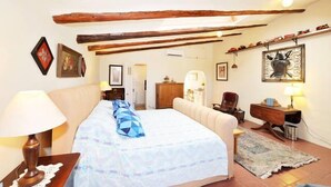 Een slaapkamer met een bed, een nachtkastje, een bureau, een stoel en een plank met boeken.