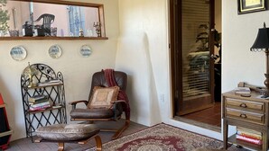 Een gezellige woonkamer met een leren fauteuil, een klein tafeltje met boeken, een kamerkleed met dessin en een boekenkast.