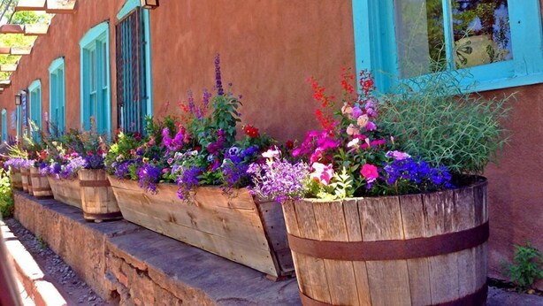 Een gebouw met houten plantenbakken langs de buitenmuur, gevuld met kleurrijke bloemen.