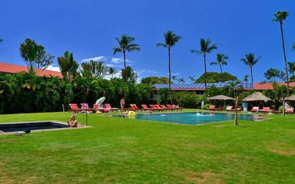A pool area with lounge chairs and palm trees.