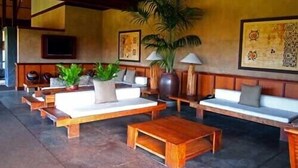 A spacious lobby with wooden furniture, including sofas and a coffee table, and a large plant. - Aina Nalu Studio, Great Rates & Location, AC & WIFI,  2 Pools & Jacuzzi (Lahaina)