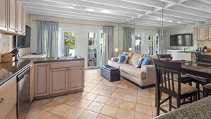 A spacious kitchen with a central island, a dining area with a table and chairs, and a living room with a sofa and a TV.