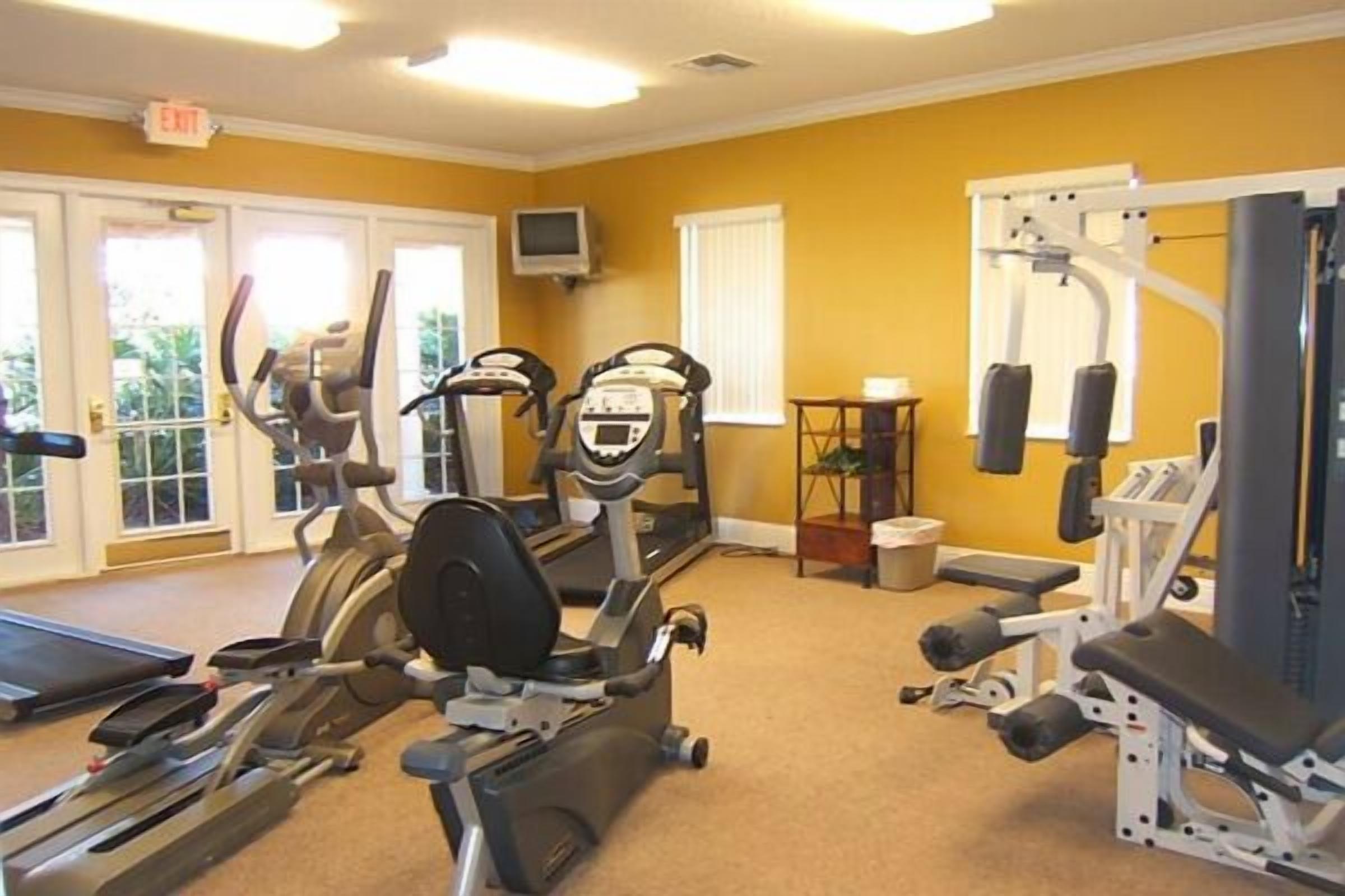 Ein Fitnessstudio mit Laufbändern, Crosstrainern und Gewichten.
