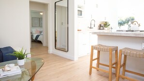 A modern apartment with a living area, a kitchen with a large mirror, and a small dining area.