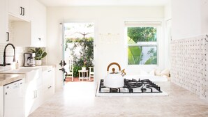 A modern kitchen with white cabinets, a gas stove, and a view of the garden through the window.