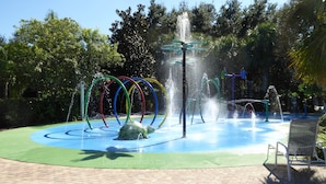 Una fuente de agua con múltiples chorros y anillos de colores en un parque.