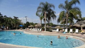 Piscina com espreguiçadeiras e palmeiras.