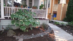 A house with a porch, potted plants, and a garden with rocks and mulch. - Pet friendly apartment with covered patio and fenced-in yard. (Portland)