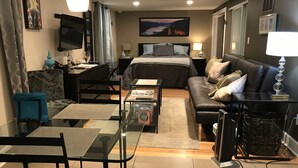 A modern hotel room with a bed, a sofa, a desk, and a TV. - Pet friendly apartment with covered patio and fenced-in yard. (Portland)