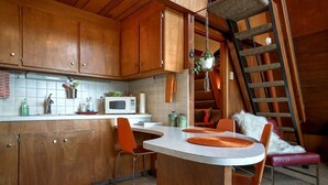 A compact kitchen with wooden cabinets, a microwave, and a small dining area with a round table and two chairs.