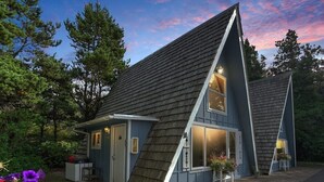 A small, single-story house with a steeply pitched roof, a front porch, and a garage.