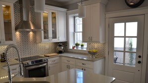 Una cocina moderna con armarios blancos, una campana de acero inoxidable, horno empotrado y una isla grande con lavamanos.
