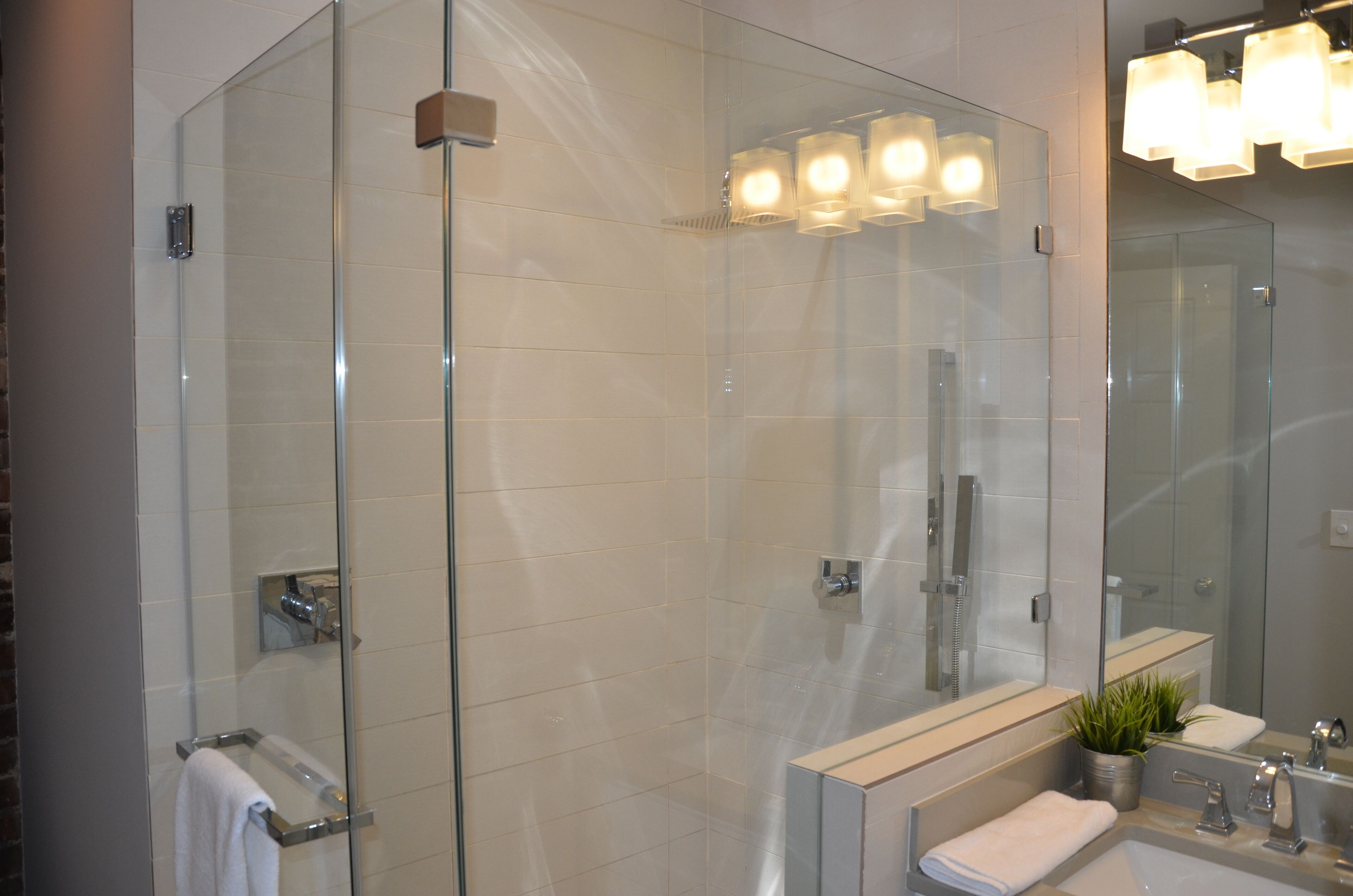 Un baño moderno con cabina de ducha de vidrio, un espejo grande y un lavabo con toallero.