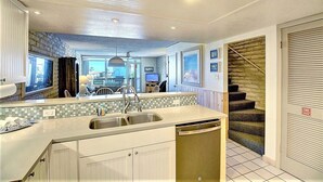 A kitchen with a central island, a dishwasher, and a staircase leading to a landing.