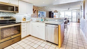 A modern kitchen with white cabinets, a built-in oven, microwave, and dishwasher.