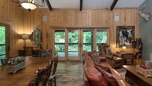 Ein Holzinterieur mit einem Esstisch, Stühlen, einem Ledersofa und einem Kamin.