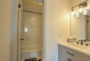 Bañera con ducha, secador de pelo, toallas, shampoo