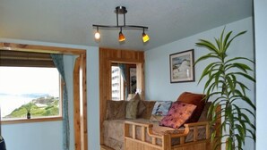 Una habitación acogedora con un banco de madera, un ventanal con vistas, una planta y una lámpara en el techo.