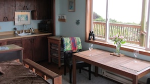 Una cocina compacta con armarios de madera, una mesa de comedor con un mantel individual, un banco y una ventana con vistas a una terraza de madera.