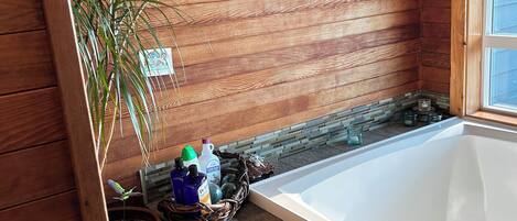 A bathroom with wooden walls, a bathtub, and a potted plant.