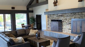 A spacious living room with a stone fireplace, dark wood flooring, and modern furniture. - Big Piney Family Fun (Eden)