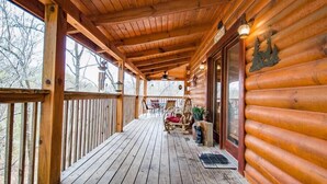 Une cabane en bois dotée d’un porche couvert, d’un ventilateur de plafond et offrant une vue sur les arbres environnants.