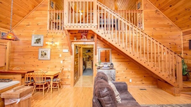 L’intérieur d’une cabane en bois comprend un coin repas, un canapé et un escalier menant à une mezzanine.