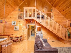 L’intérieur d’une cabane en bois comprend un coin repas, un canapé et un escalier menant à une mezzanine.
