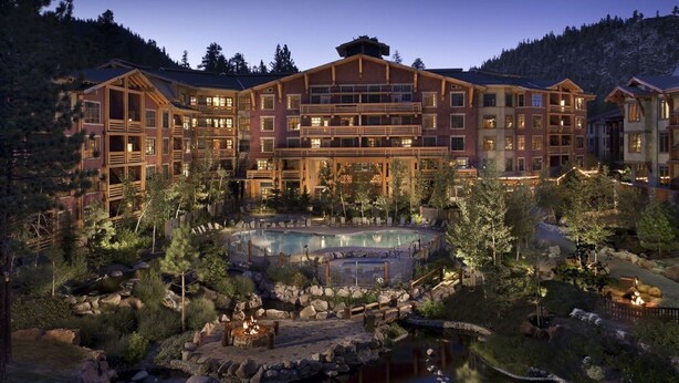 A large lodge with multiple guest rooms, a central courtyard with a swimming pool, and a fire pit area.