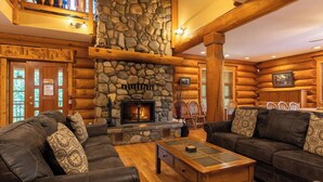 A log cabin interior with a stone fireplace, leather sofas, and wooden furniture. - Ski In/Out to your Hot Tub. Pool Table (Fernie)
