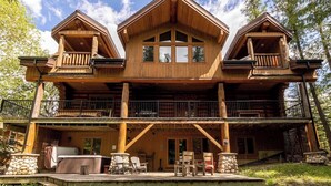 A two-story wooden cabin with a balcony, outdoor seating area, and a hot tub. - Ski In/Out to your Hot Tub. Pool Table (Fernie)