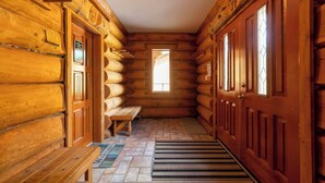 A log cabin interior with a wooden bench, a welcome mat, and a window. - Ski In/Out to your Hot Tub. Pool Table (Fernie)