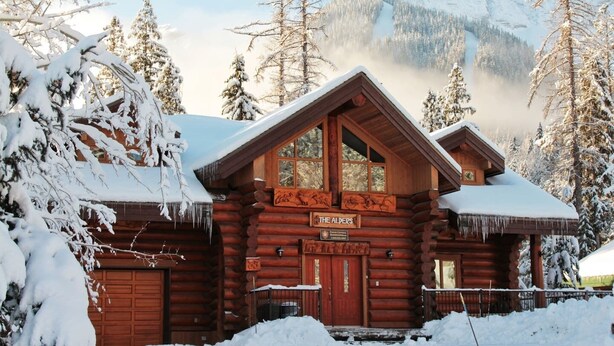 A log cabin with a sign reading "The Alders." It features a wooden exterior, a large window, and a garage door. - Ski In/Out to your Hot Tub. Pool Table (Fernie)